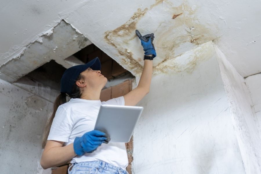 Water damage restoration professional conducting initial assessment with moisture detection equipment